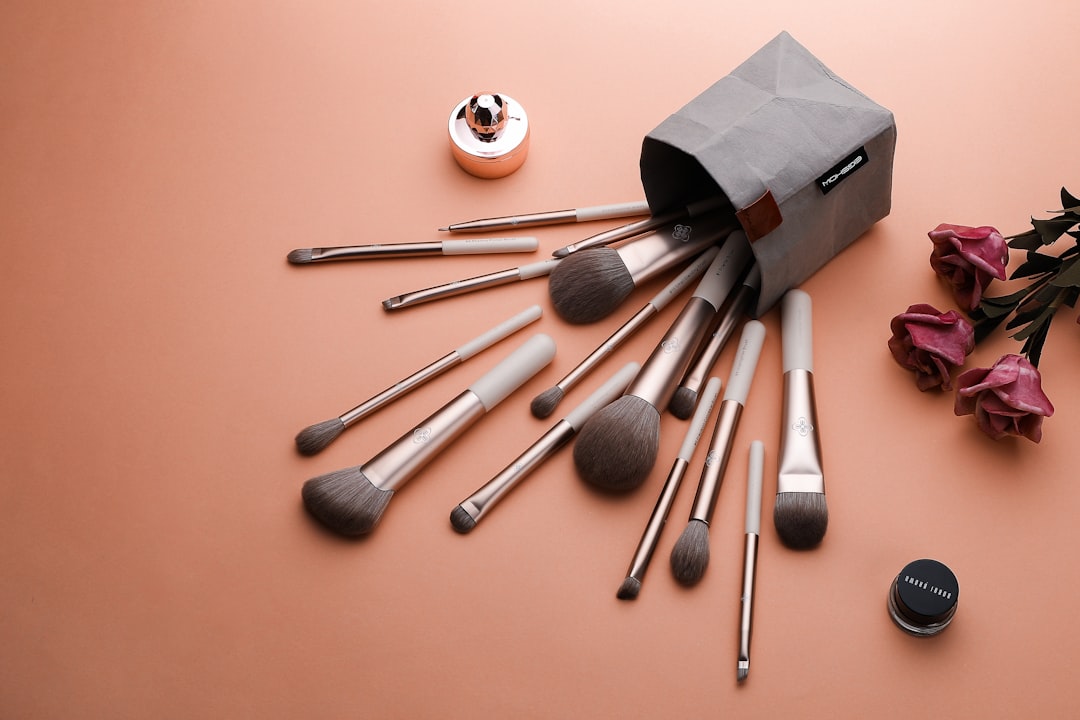 Makeup brushes spilling from a gray fabric holder onto an orange surface