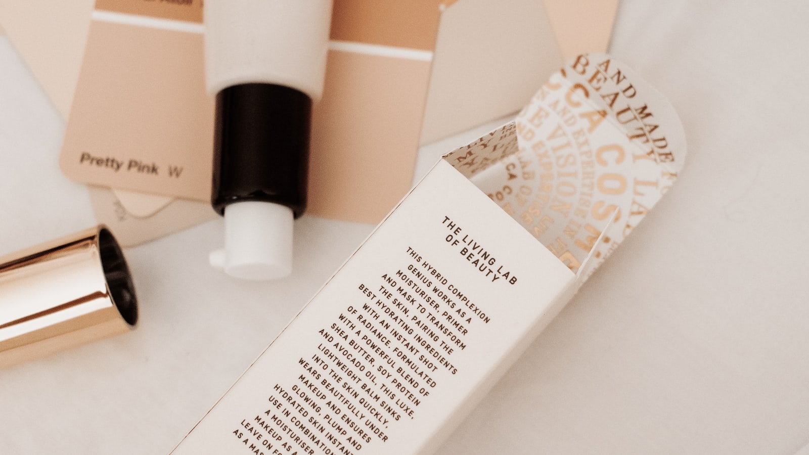 A tube with a black and white pump sits next to an open cardboard box