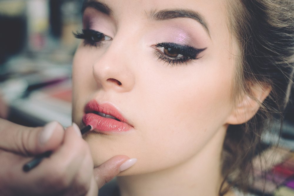 Close-up of a person applying makeup to another person's lips