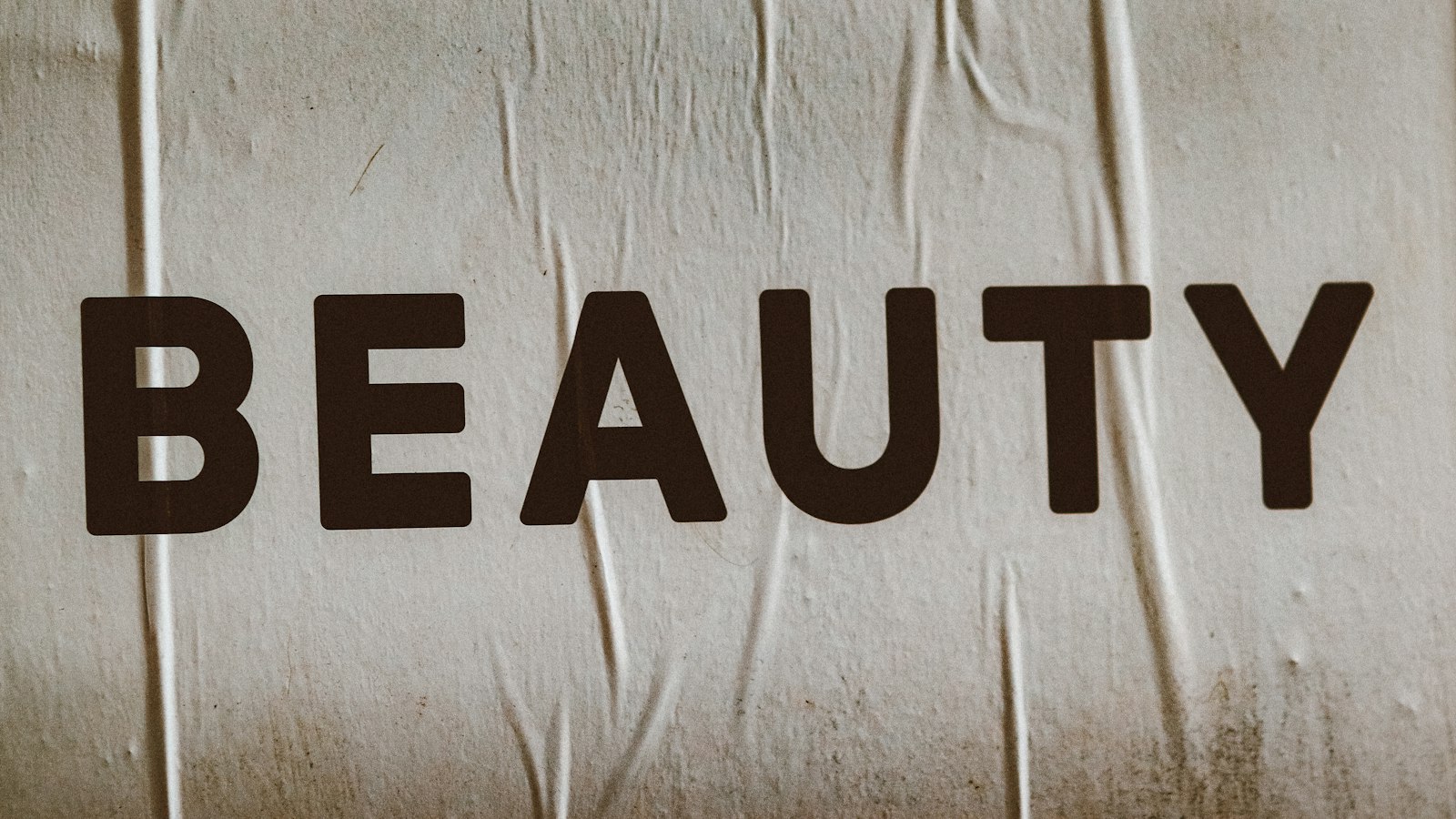 The word BEAUTY printed in black capital letters on wrinkled and textured light-colored paper