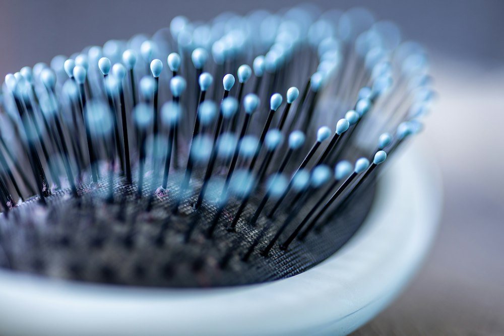 Close-up of a hairbrush with thin black bristles and blue ball tips