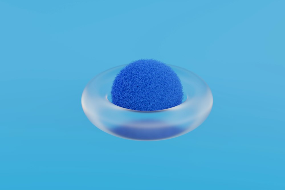 A fuzzy blue sphere rests inside a transparent glass ring on a blue background