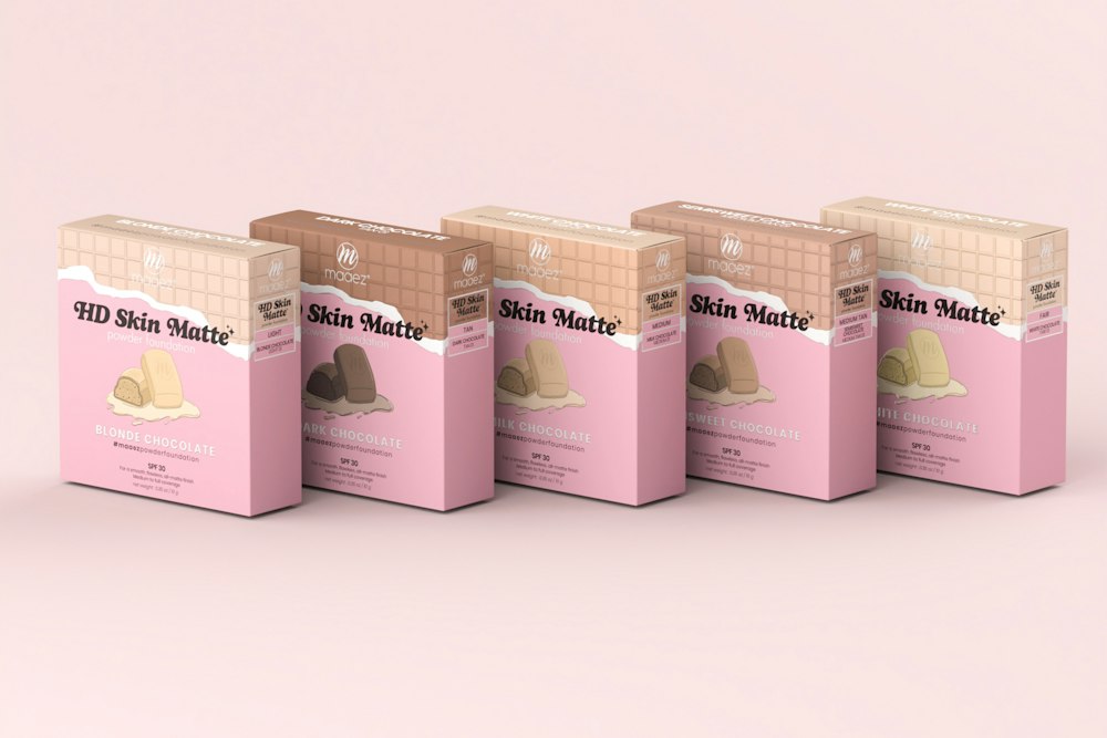 Five square pink and brown boxes of powder foundation arranged in a row