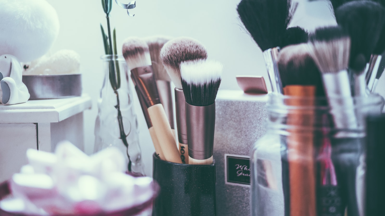 A collection of makeup brushes stands in a dark holder on a tabletop