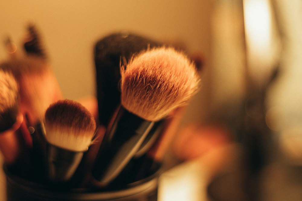 Close-up of several makeup brushes with dark handles in a container