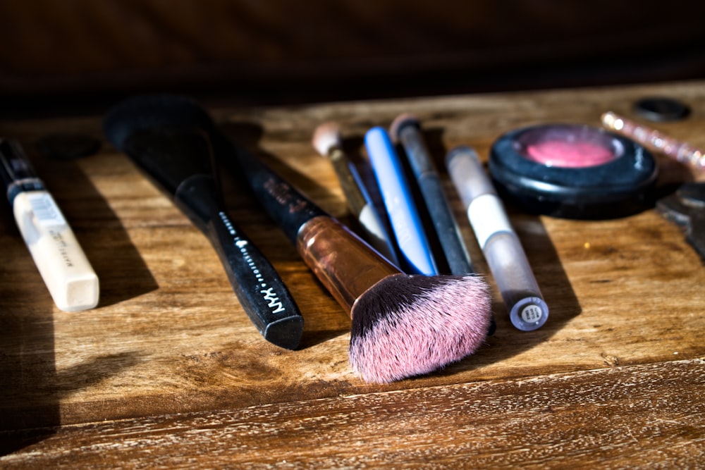 Makeup brushes and cosmetics scattered on a wooden surface