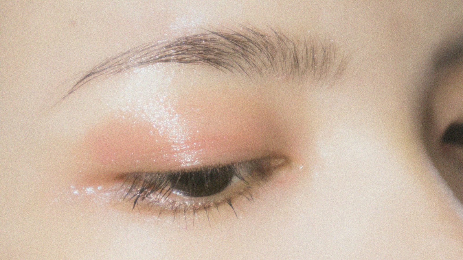 A close-up of a person's closed eye with light makeup and a defined eyebrow