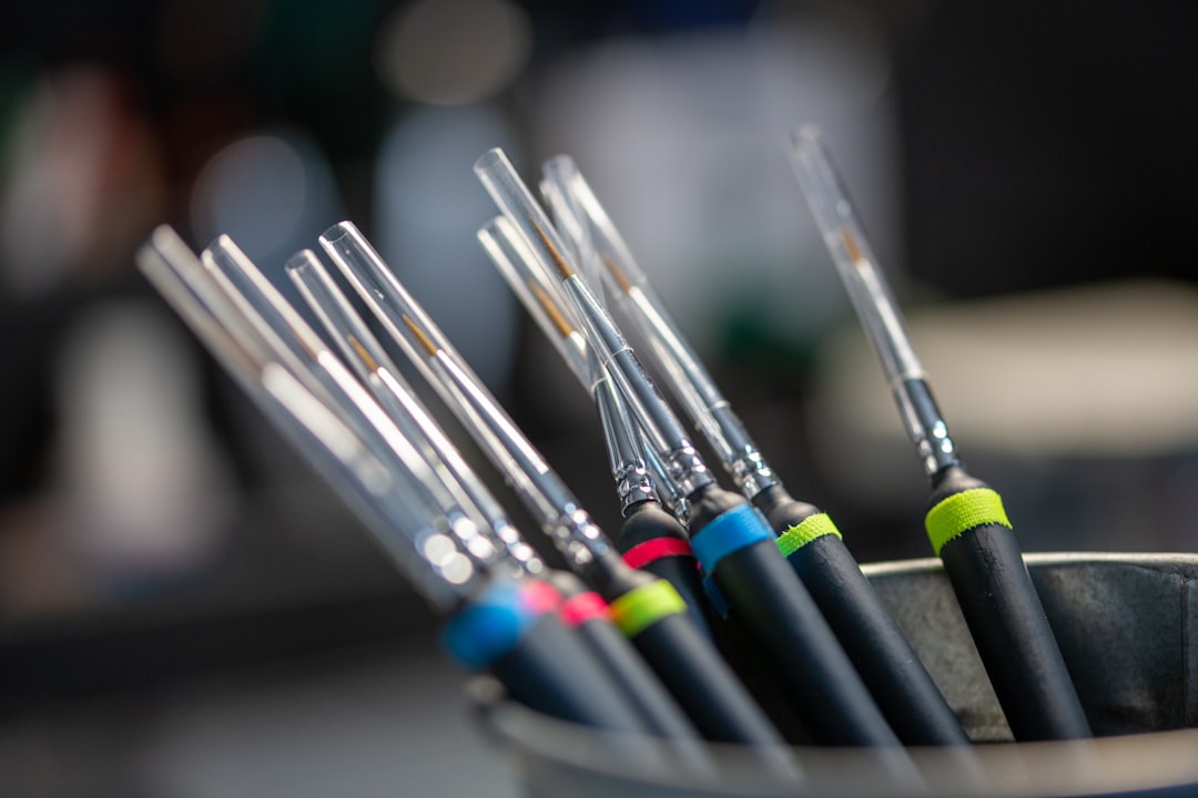 A bunch of fine-tipped detail brushes with clear caps in a metal cup