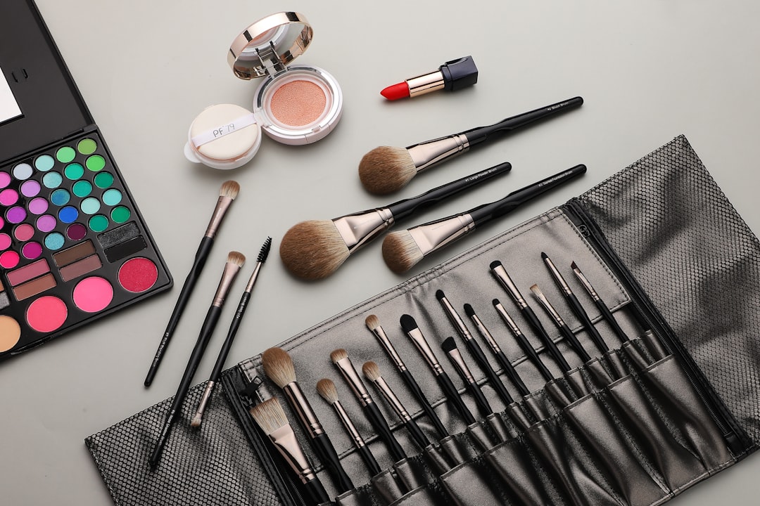 Overhead shot of a makeup palette, compact, lipstick, and various brushes