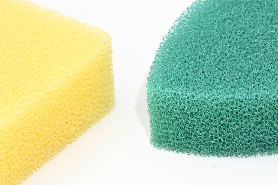 A yellow sponge and a green sponge sit side-by-side on a white surface